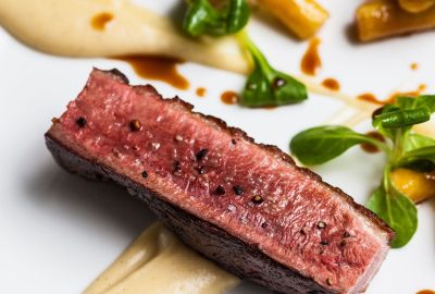 Magret de pato con salsa de guarapo y aceto, cebollas confitadas y crujiente de plátano